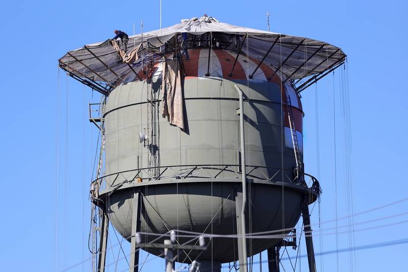Painters find themselves over one-hundred feet up as they make adjustments to the dust protection while painting the New Bedford water tower on August 25, 2026.  PHOTO PETER PEREIRA