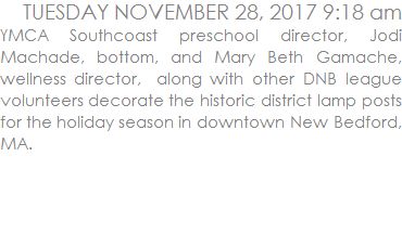 YMCA Southcoast preschool director, Jodi Machade, bottom, and Mary Beth Gamache, wellness director,  along with other DNB league volunteers decorate the historic district lamp posts for the holiday season in downtown New Bedford, MA.