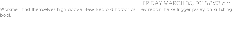 Workmen find themselves high above New Bedford harbor as they repair the outrigger pulley on a fishing boat.