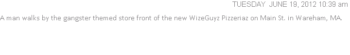 A man walks by the gangster themed store front of the new WizeGuyz Pizzeriaz on Main St. in Wareham, MA.