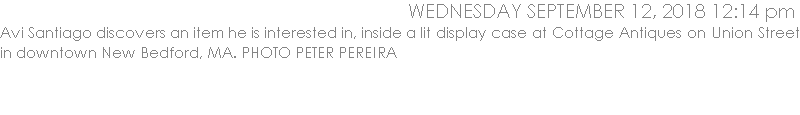 Avi Santiago discovers an item he is interested in, inside a lit display case at Cottage Antiques on Union Street in downtown New Bedford, MA. PHOTO PETER PEREIRA