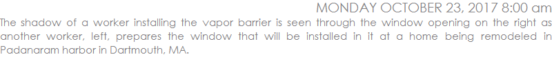 The shadow of a worker installing the vapor barrier is seen through the window opening on the right as another worker, left, prepares the window that will be installed in it at a home being remodeled in Padanaram harbor in Dartmouth, MA.