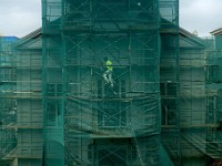 A JAG Painters worker makes his way up the staging in front of the Seamen's Bethel in downtown New Bedford, behind a protective green cover.