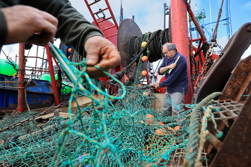 Pedro Cura lends a hand to the crew of his boat f/v Fisherman as they make repairs to the groundfishing nets before heading back out to sea from New Bedford, MA. PHOTO PETER PEREIRA
