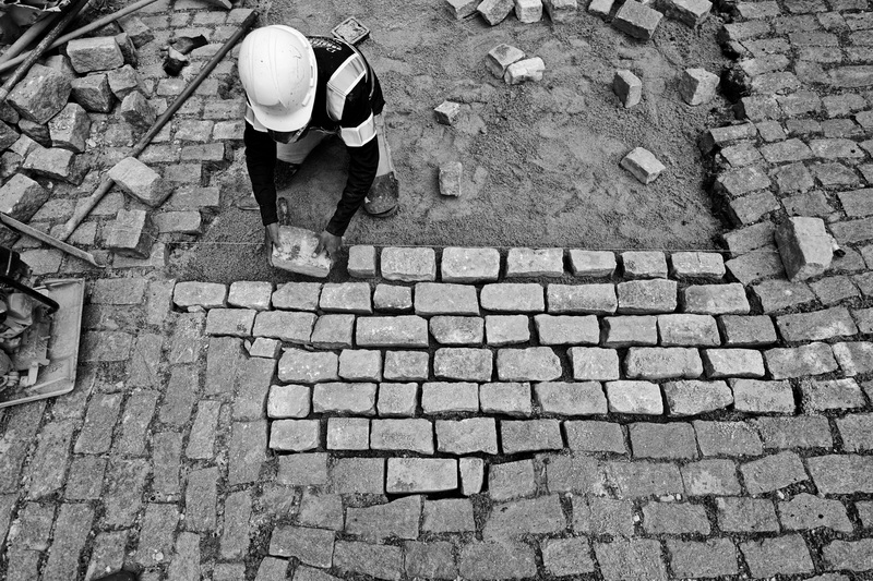 A D&C Construction stone worker, rebuilds the cobblestone road on Roadman Street in New Bedford, MA after Eversource performed repairs to lines underground. PHOTO PETER PEREIRA