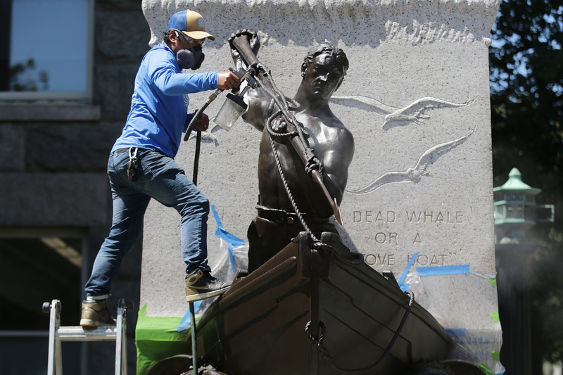 Gompo Yarmolinsky of Daedalus sprays an acrylic coat on the iconic whaleman statue in front of the New Bedford Free Public Library after the bronze statue was restored to its former glory.  PHOTO PETER PEREIRA