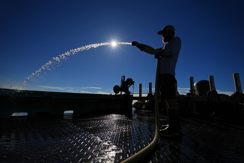 Chris Fisher, captain, hoses down the deck of the Big Lu oyster boat, before heading back out to sea from Westport harbor. PHOTO PETER PEREIRA