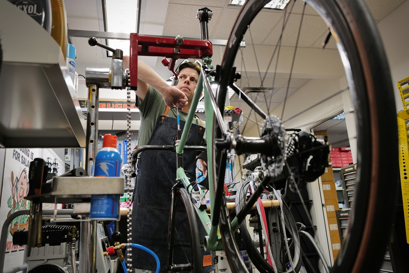 Matt Neugebauer tightens the handlebar stem on a vintage Bianchi bicycle he is building at his shop in New Bedford.  Mr. Neugebauer sells his bicycles and cycling equipment strictly on eBay under the House of Cogs name and has sold over 50k items. PHOTO PETER PEREIRA