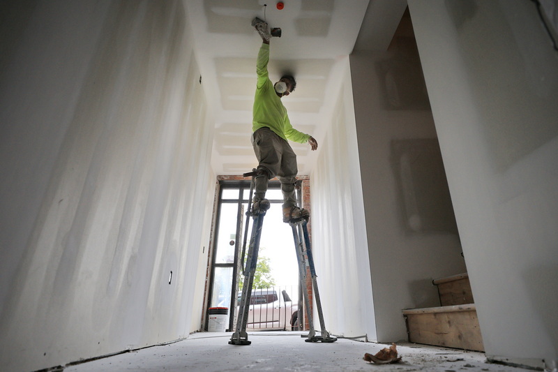 A painter sands stands tall atop some stilts as he sands the ceiling of the entrance to the future Elmwater Landing apartment complex at the intersection of Elm Street and N Water Street in New Bedford, MA. PHOTO PETER PEREIRA