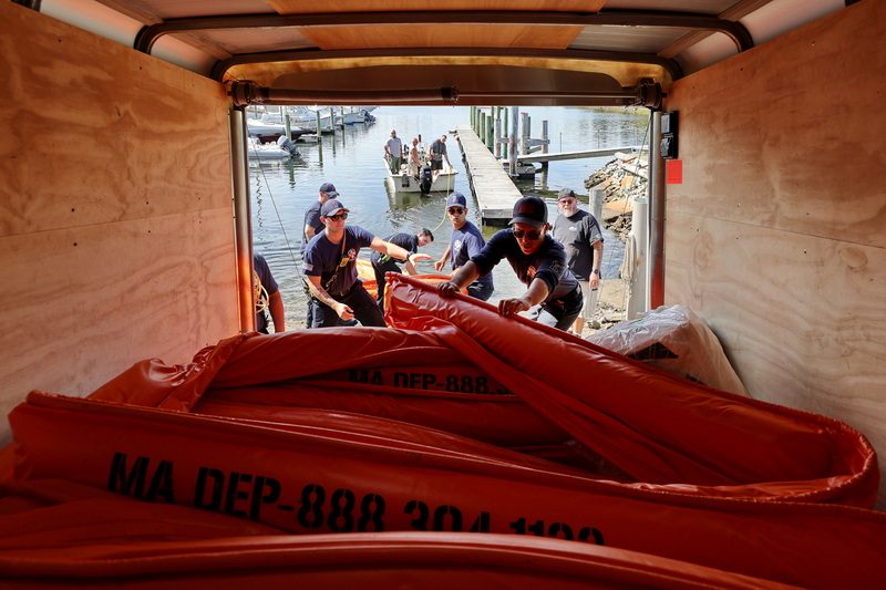 Fairhaven Harbormaster Timothy Cox, right, looks on as Fairhaven firefighters Brad Johnson, John Cox, Cody Piche, Ryan Amado and Spencer Espinoza pull a containment boom from the back of a trailer during a First Responder Training Geographic Response Strategy Training exercise by the Mass EPA Marine Oil Spill Prevention and Response Program instituted after the 2003 oil spill in Buzzards Bay.  The boom will be towed out by the boat seen in the background and placed around a fishing boat docked in Fairhaven as part of the three year rotation exercise involving New Bedford fire and police departments, Fairhaven fire, Acushnet fire and the Harbormaster.  PHOTO PETER PEREIRA