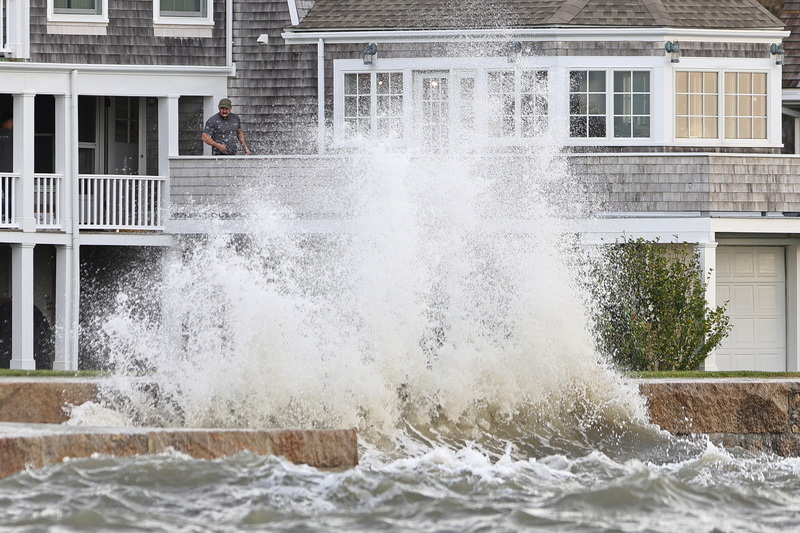 A man looks down as heavy surf crashes into the seawall in front of a home in Mattapoisett, MA as a storm surge makes its way across the region. PHOTO PETER PEREIRA