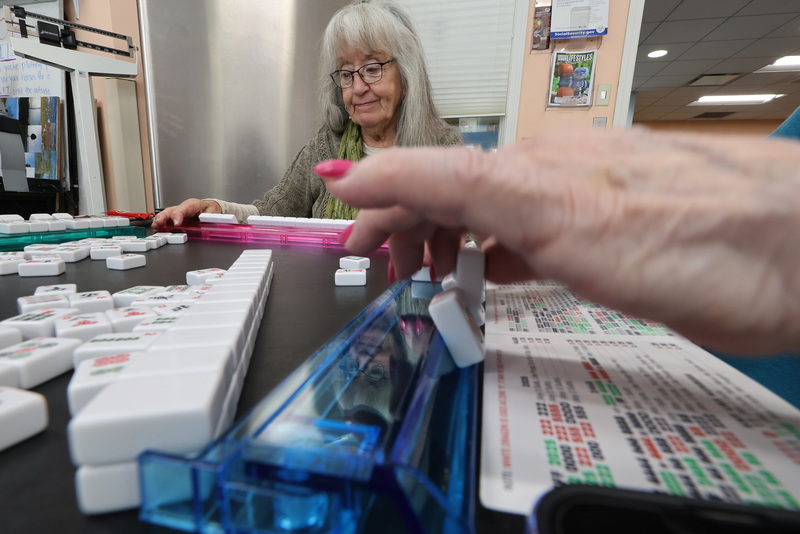 Maureen Beaudoin is reflected on the piece holder of Geri Giusti as she prepares to make her move during a game of Mahjong at the Fairhaven Council on Aging on Huttleston Avenue in Fairhaven, MA. PHOTO PETER PEREIRA