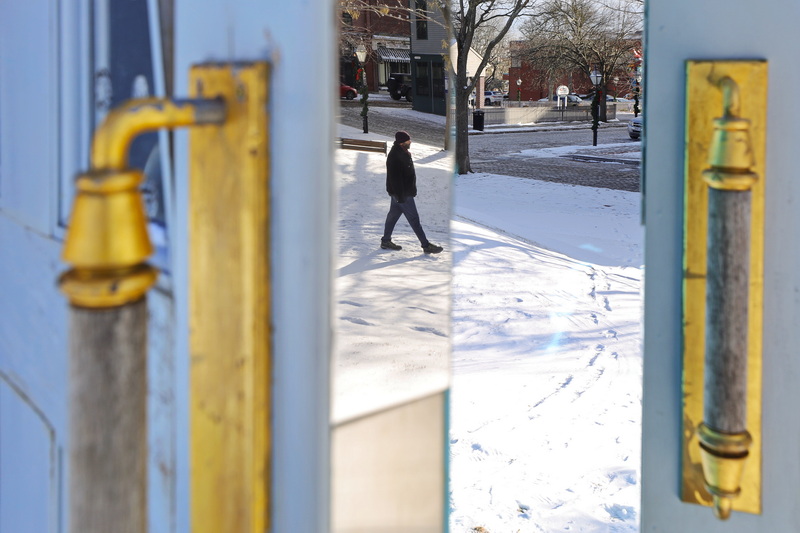 On a chilly afternoon, a man�s reflection appears on the mirrored edge of the large door sculpture named 'Threshold,' located at Custom House Square in New Bedford, MA. PHOTO PETER PEREIRA
