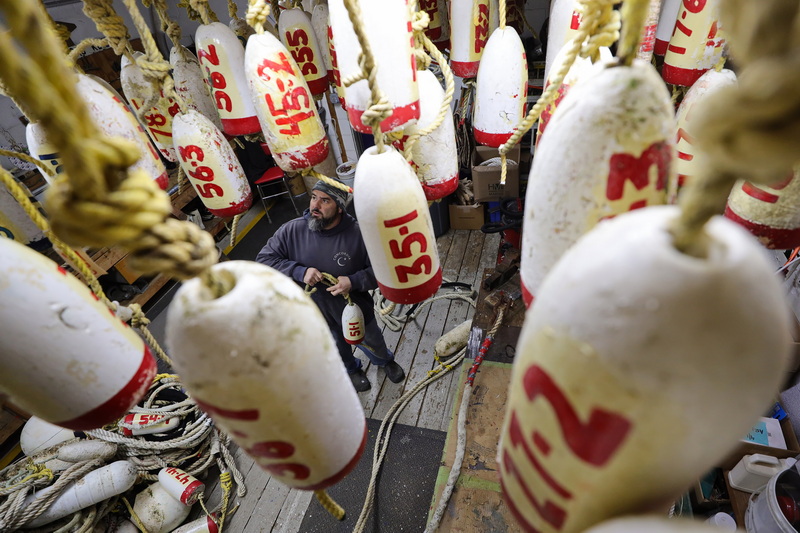 Chris Dumas, the mooring manager, glances upward to find a spot to hang the float marker alongside the others already complete suspended from the rafters at the Concordia Company in Dartmouth, MA. PHOTO PETER PEREIRA