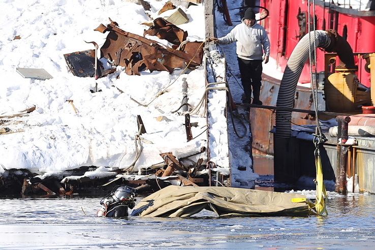 Jonathan Hughes from C&H Marine is immersed in icy conditions as he plunges into the cold Acushnet River to secure a lift bag to a submerged barge in New Bedford, MA. PHOTO PETER PEREIRA