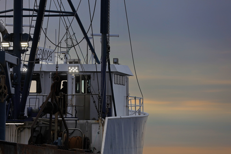 In the early morning, the outline of a fisherman is visible inside the wheelhouse of a fishing vessel docked in Fairhaven, MA as it prepares to head out to sea. PHOTO PETER PEREIRA