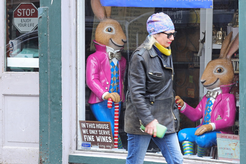 Two rabbit figures look on from inside of the New Bedford Merchant Gift Shop as a woman walks up William Street in New Bedford, MA. PHOTO PETER PEREIRA
