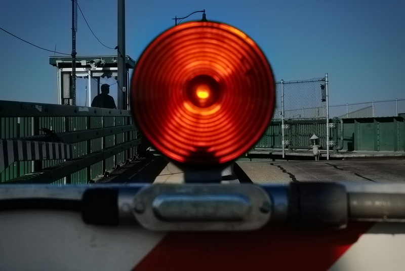 Padanaram bridge operator Steve Catana is seen in the control booth lowering the gate and activating the warning lights while opening the bridge to allow boat traffic to cross in Dartmouth, MA. PHOTO PETER PEREIRA
