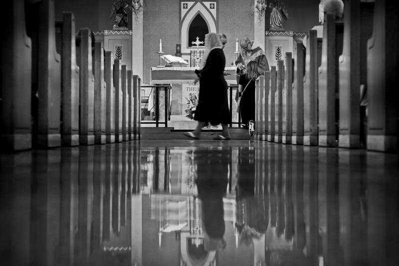 Father Maximilian gives the Eucharist host to a parishioner during mass at Our Lady's Chapel in New Bedford, MA as another parishioner heads back to her seat after receiving hers. PHOTO PETER PEREIRA