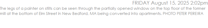 The legs of a painter on stilts can be seen through the partially opened window on the top floor of the former mill at the bottom of Elm Street in New Bedford, MA being converted into apartments. PHOTO PETER PEREIRA