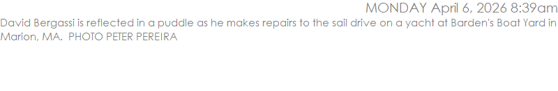 David Bergassi is reflected in a puddle as he makes repairs to the sail drive on a yacht at Barden's Boat Yard in Marion, MA.  PHOTO PETER PEREIRA