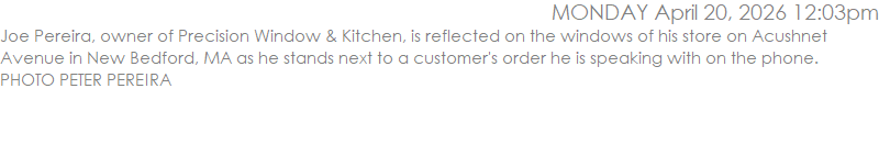 Joe Pereira, owner of Precision Window & Kitchen, is reflected on the windows of his store on Acushnet Avenue in New Bedford, MA as he stands next to a customer's order he is speaking with on the phone. PHOTO PETER PEREIRA