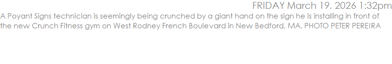 A Poyant Signs technician is seemingly being crunched by a giant hand on the sign he is installing in front of the new Crunch Fitness gym on West Rodney French Boulevard in New Bedford, MA. PHOTO PETER PEREIRA